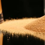 Receita de Sal Dourado para Temperar Seus Pratos a pile of sand next to a glass of beer
