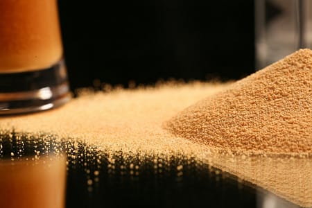 a pile of sand next to a glass of beer
