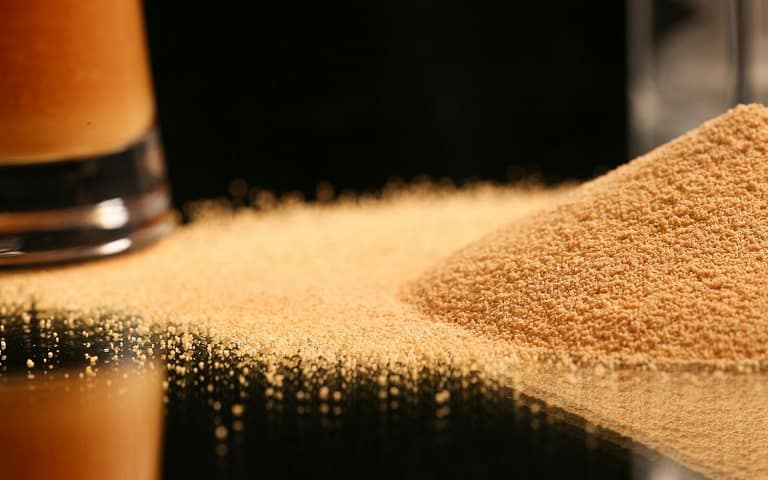 Receita de Sal Dourado para Temperar Seus Pratos a pile of sand next to a glass of beer